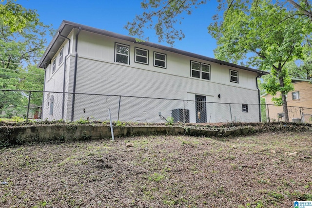 back of house featuring fence and brick siding