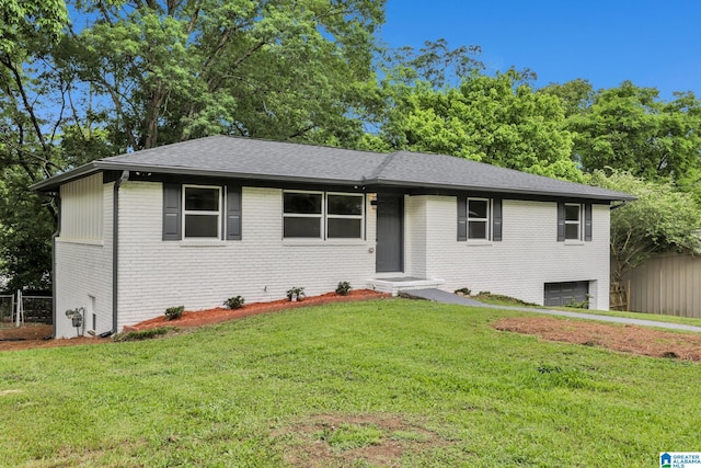 ranch-style home featuring fence, a shingled roof, brick siding, a garage, and a front yard