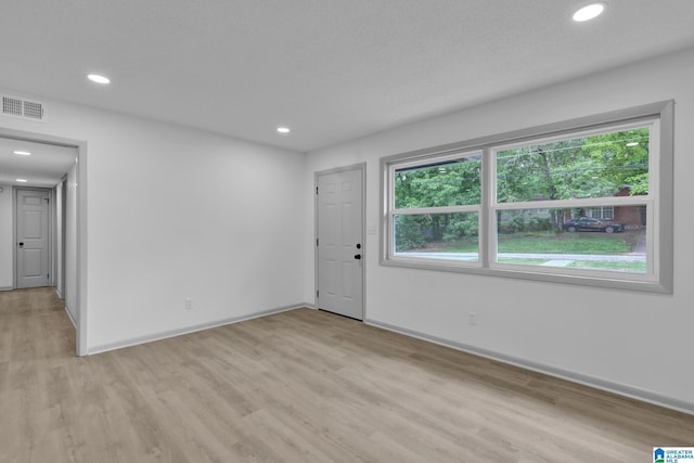 empty room featuring light wood-style floors, a wealth of natural light, recessed lighting, and visible vents