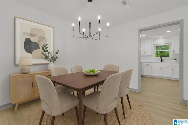 dining space featuring baseboards, a chandelier, visible vents, and light wood-style floors