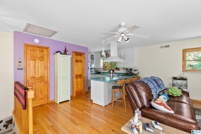 323 Taylor Rd, Remlap, AL 35133 - kitchen with island range hood, a peninsula, light wood-style flooring, a ceiling fan, and white cabinets