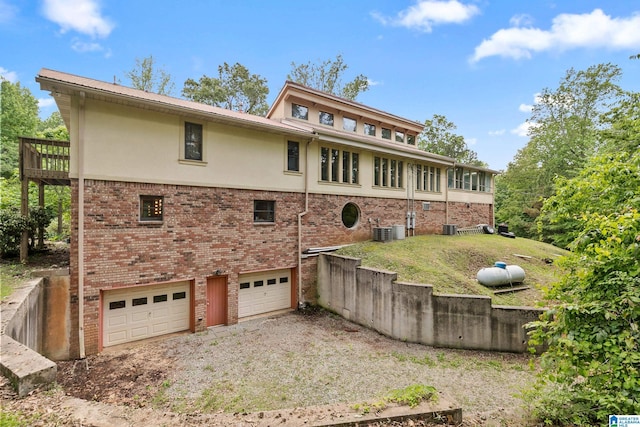 323 Taylor Rd, Remlap, AL 35133 - rear view of house with stucco siding, an attached garage, driveway, brick siding, and cooling unit