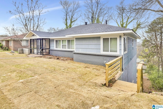 2636 20th Pl, Birmingham, AL 35208 - view of front of home featuring roof with shingles, a sunroom, a front lawn, and brick siding
