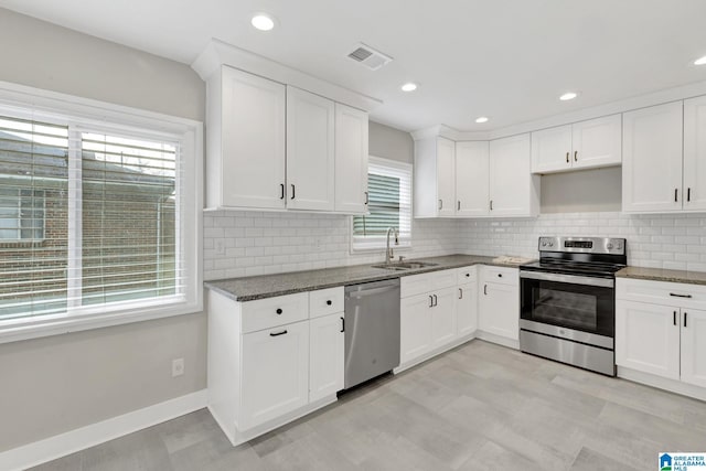 2636 20th Pl, Birmingham, AL 35208 - kitchen with white cabinets, a sink, dark stone counters, stainless steel appliances, and visible vents