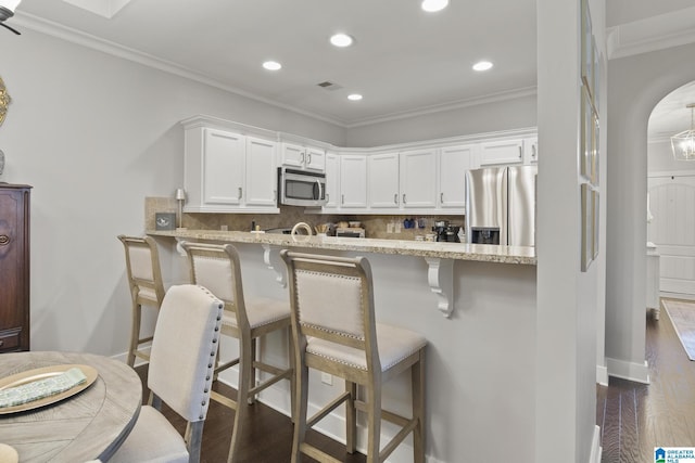 1204 Grants Way, Irondale, AL 35210 - kitchen with stainless steel appliances, arched walkways, dark wood finished floors, white cabinets, and crown molding