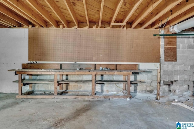 unfinished below grade area featuring concrete block wall and a workshop area