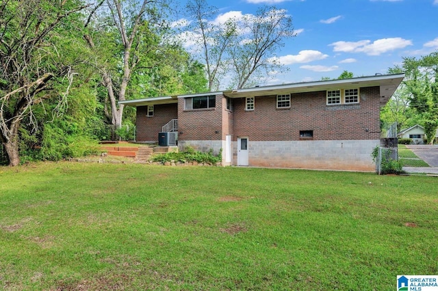 rear view of house with crawl space, a lawn, central air condition unit, brick siding, and fence