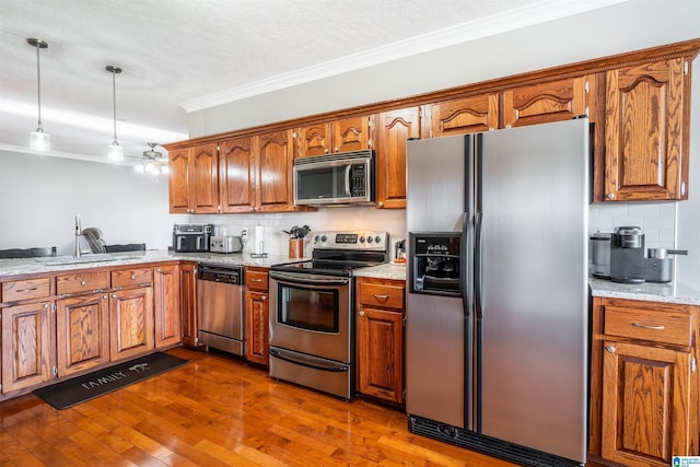 145 Cameron Ct, Alexandria, AL 36250 - kitchen with appliances with stainless steel finishes, tasteful backsplash, brown cabinets, a sink, and ornamental molding