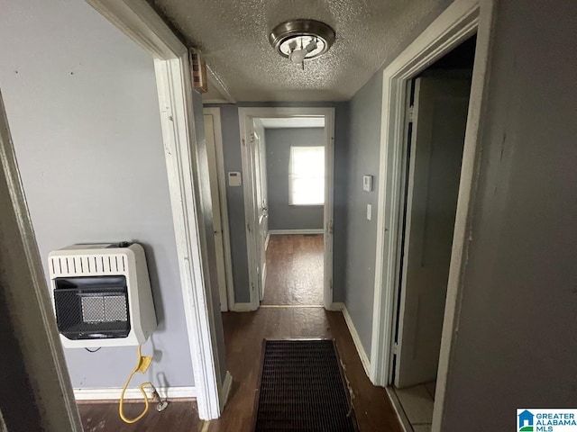 hallway with baseboards, a textured ceiling, heating unit, and wood finished floors