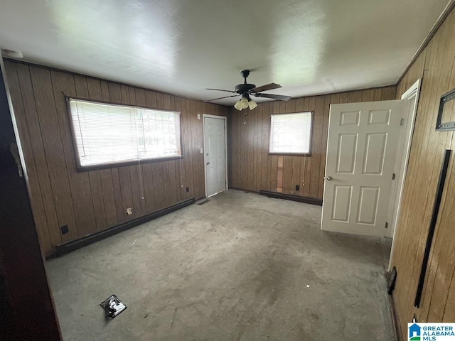 unfurnished bedroom featuring wood walls, carpet, and ceiling fan