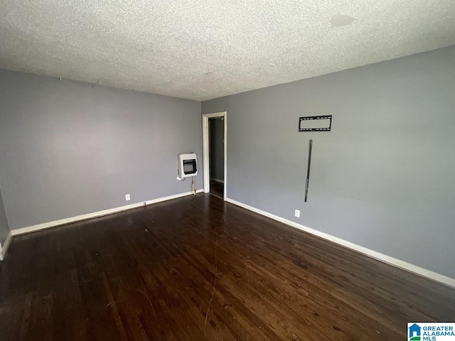 empty room featuring heating unit, baseboards, dark wood-style floors, and a textured ceiling