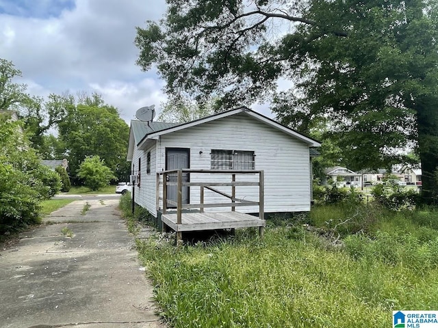 view of side of property featuring a wooden deck and driveway