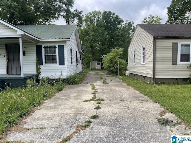 view of side of property featuring a porch, driveway, crawl space, and metal roof