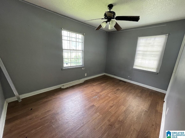 spare room featuring baseboards, a ceiling fan, dark wood finished floors, and a textured ceiling