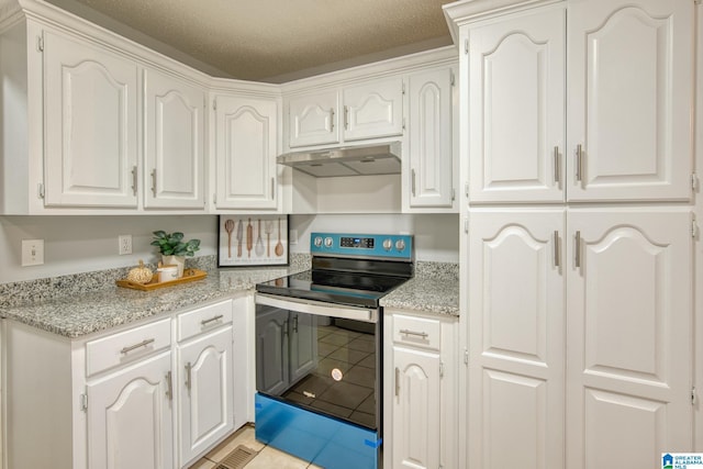 kitchen with light tile patterned flooring, light stone countertops, stainless steel electric range, white cabinetry, and under cabinet range hood