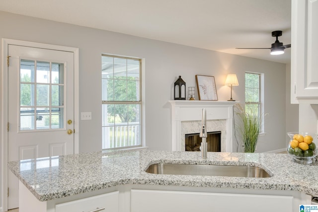 interior space featuring a premium fireplace, light stone countertops, a sink, and a healthy amount of sunlight