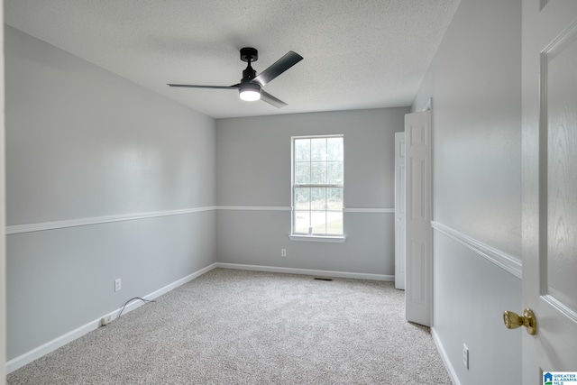 spare room featuring ceiling fan, carpet flooring, a textured ceiling, and visible vents