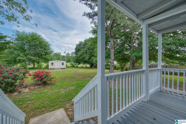 wooden deck with a storage shed, a lawn, and an outbuilding