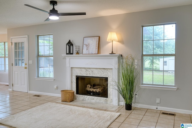 living room featuring baseboards, tile patterned flooring, a ceiling fan, and visible vents