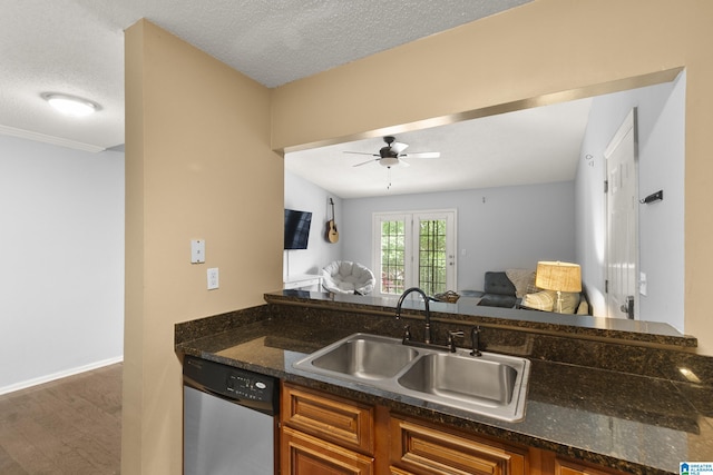 kitchen featuring brown cabinetry, a ceiling fan, open floor plan, a sink, and dishwasher