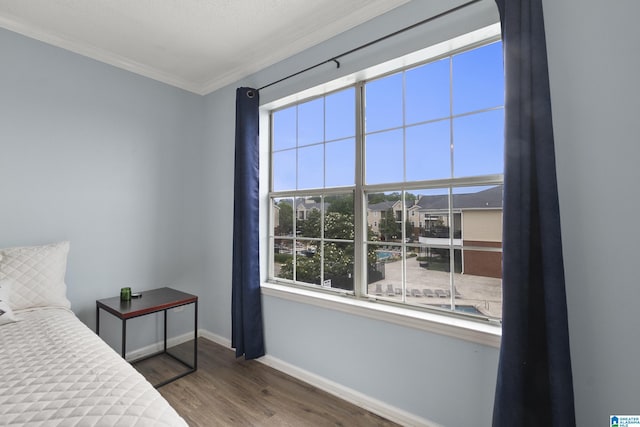 bedroom featuring baseboards, crown molding, and wood finished floors