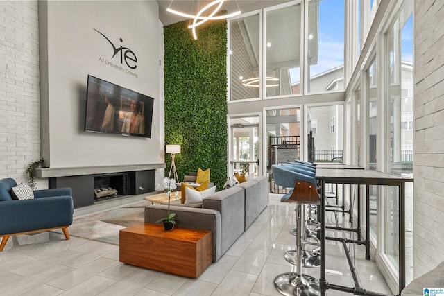 living area with a high ceiling, a chandelier, and a fireplace