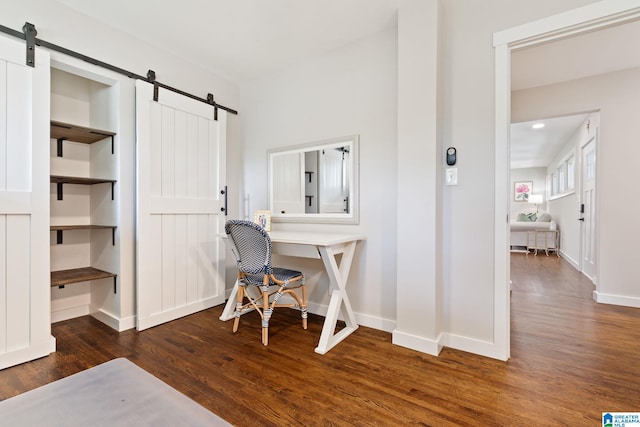 office with baseboards, a barn door, and wood finished floors