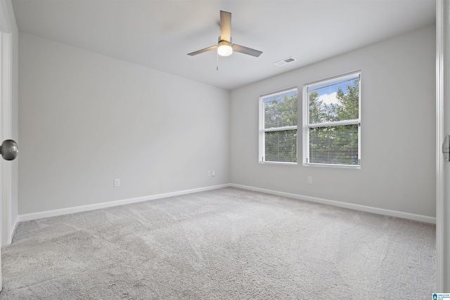 empty room with baseboards, a ceiling fan, carpet flooring, and visible vents