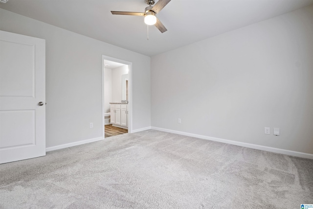 unfurnished bedroom featuring carpet floors, baseboards, ensuite bathroom, and a ceiling fan