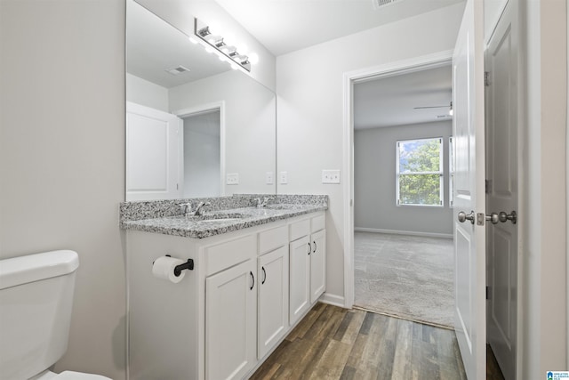 bathroom with double vanity, toilet, a sink, and wood finished floors