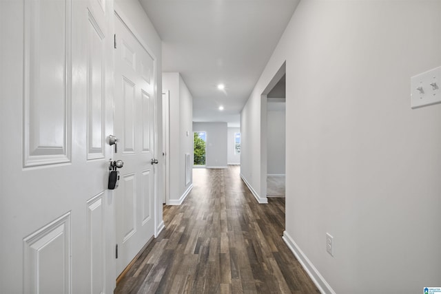 hall featuring dark wood-style flooring, baseboards, and recessed lighting