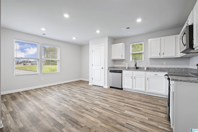 kitchen with light stone counters, plenty of natural light, appliances with stainless steel finishes, and light wood finished floors