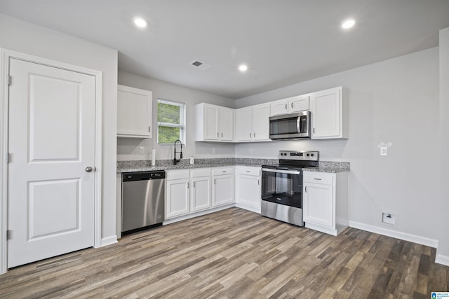 kitchen featuring light wood-style floors, light stone counters, stainless steel appliances, and white cabinetry