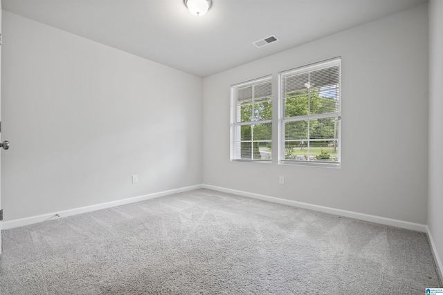 carpeted spare room featuring visible vents and baseboards