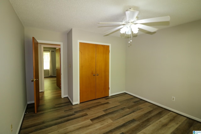 unfurnished bedroom with baseboards, a ceiling fan, dark wood finished floors, and a closet