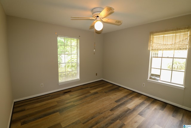 unfurnished room featuring visible vents, a ceiling fan, dark wood-style flooring, and baseboards
