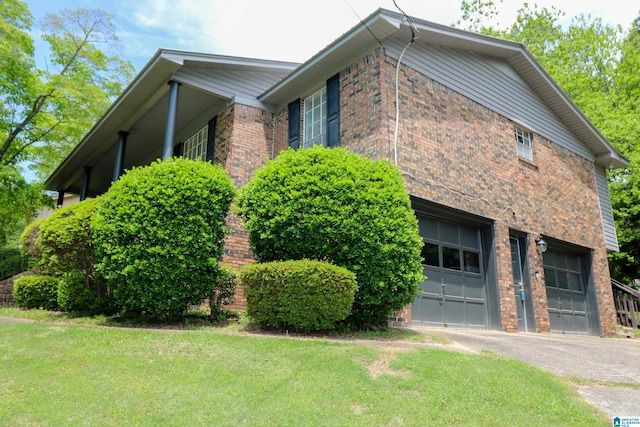 view of side of property with a lawn, an attached garage, aphalt driveway, and brick siding