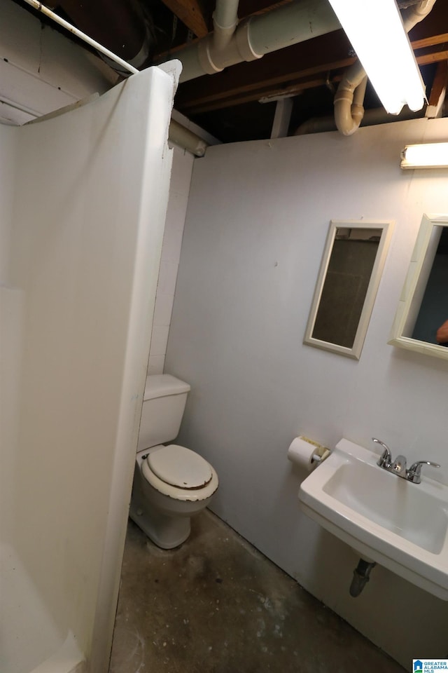 bathroom with unfinished concrete floors, toilet, and a sink