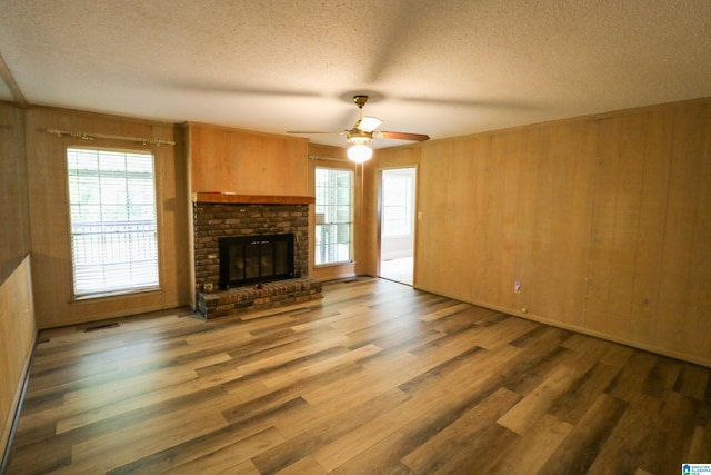 unfurnished living room with a textured ceiling, wood walls, and wood finished floors