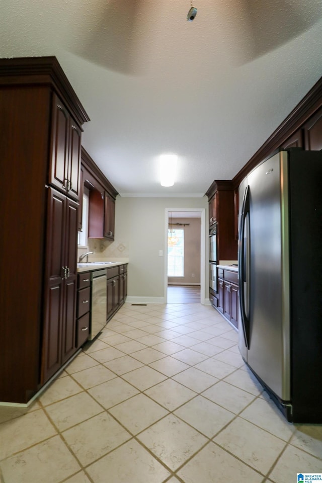 kitchen featuring appliances with stainless steel finishes, light tile patterned floors, baseboards, a sink, and light countertops