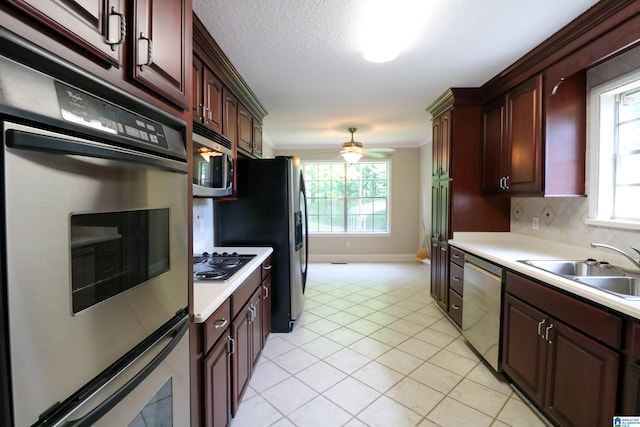 kitchen featuring a sink, light countertops, stainless steel appliances, light tile patterned floors, and a wealth of natural light