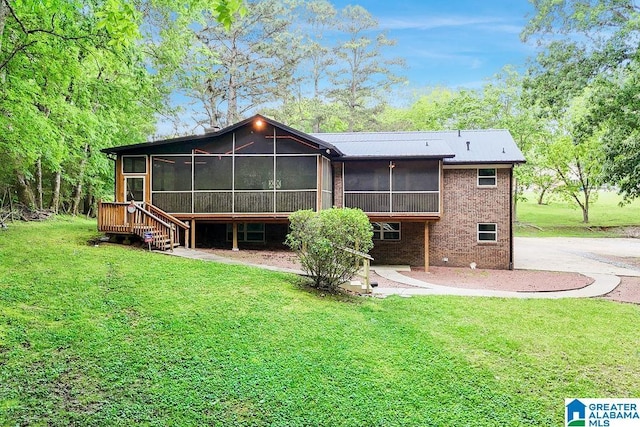 back of property with a yard, a sunroom, and brick siding