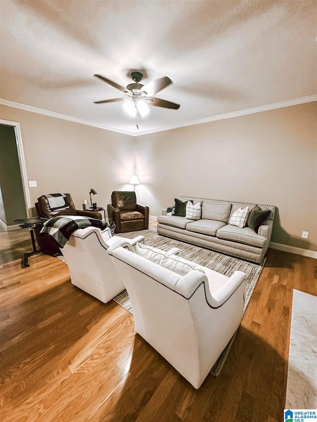 living room featuring ceiling fan, light wood-type flooring, crown molding, and baseboards