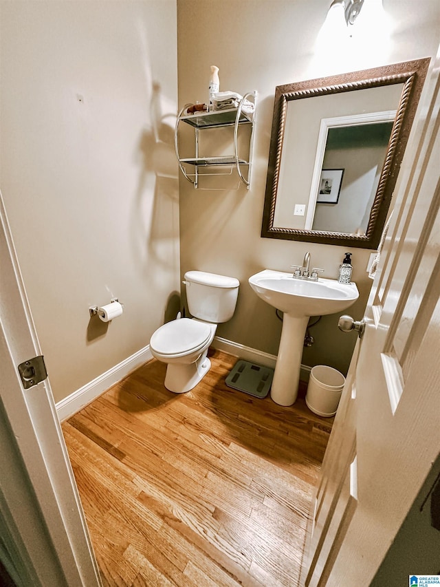bathroom with wood finished floors, toilet, and baseboards