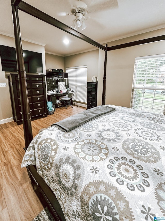 bedroom featuring ornamental molding, light wood-type flooring, an office area, baseboards, and a ceiling fan