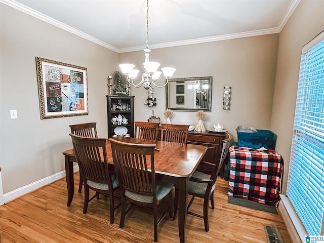 dining area featuring a chandelier, light wood-style flooring, crown molding, and healthy amount of natural light