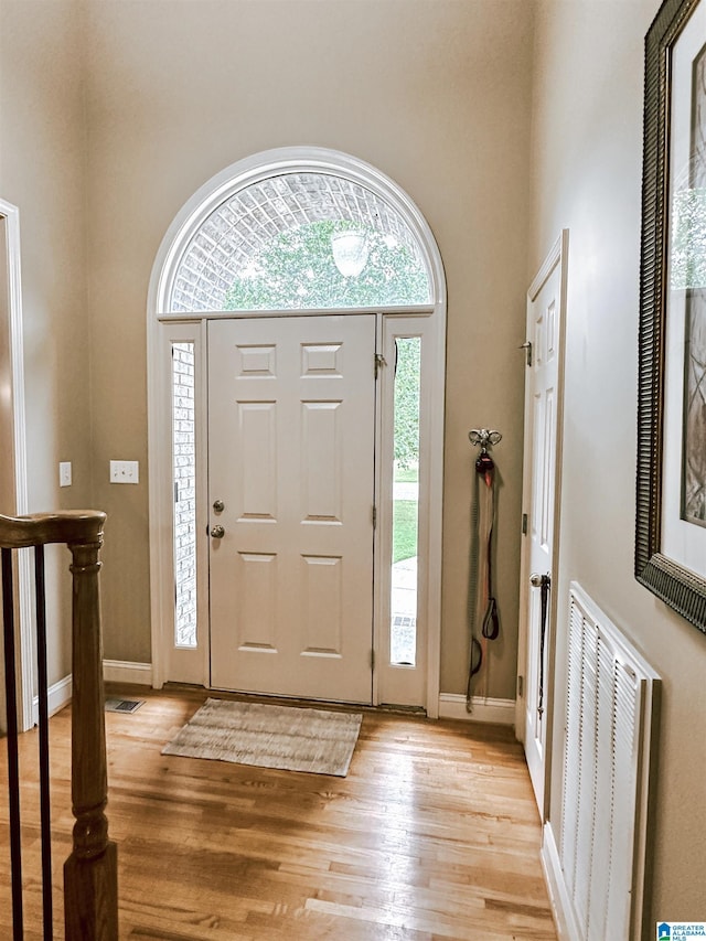 foyer entrance featuring a high ceiling, light wood-type flooring, and baseboards