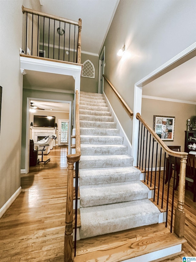 stairs featuring wood finished floors, crown molding, and baseboards