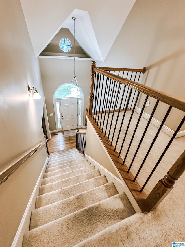 stairway featuring high vaulted ceiling, baseboards, and carpet