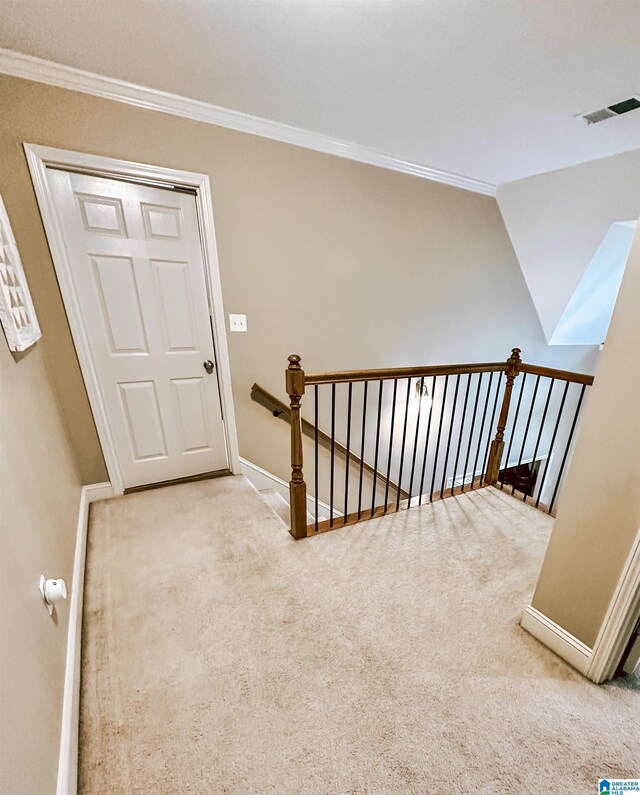 hall featuring an upstairs landing, carpet floors, crown molding, and baseboards